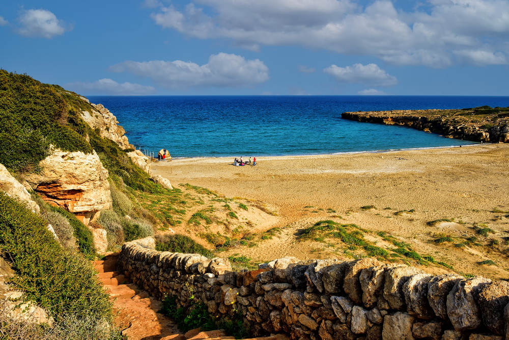 Cala sabbiosa con mare turchese tra le rocce